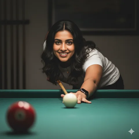 Woman in white t-shirt leaning over a pool table, cue aimed at the white ball under overhead light